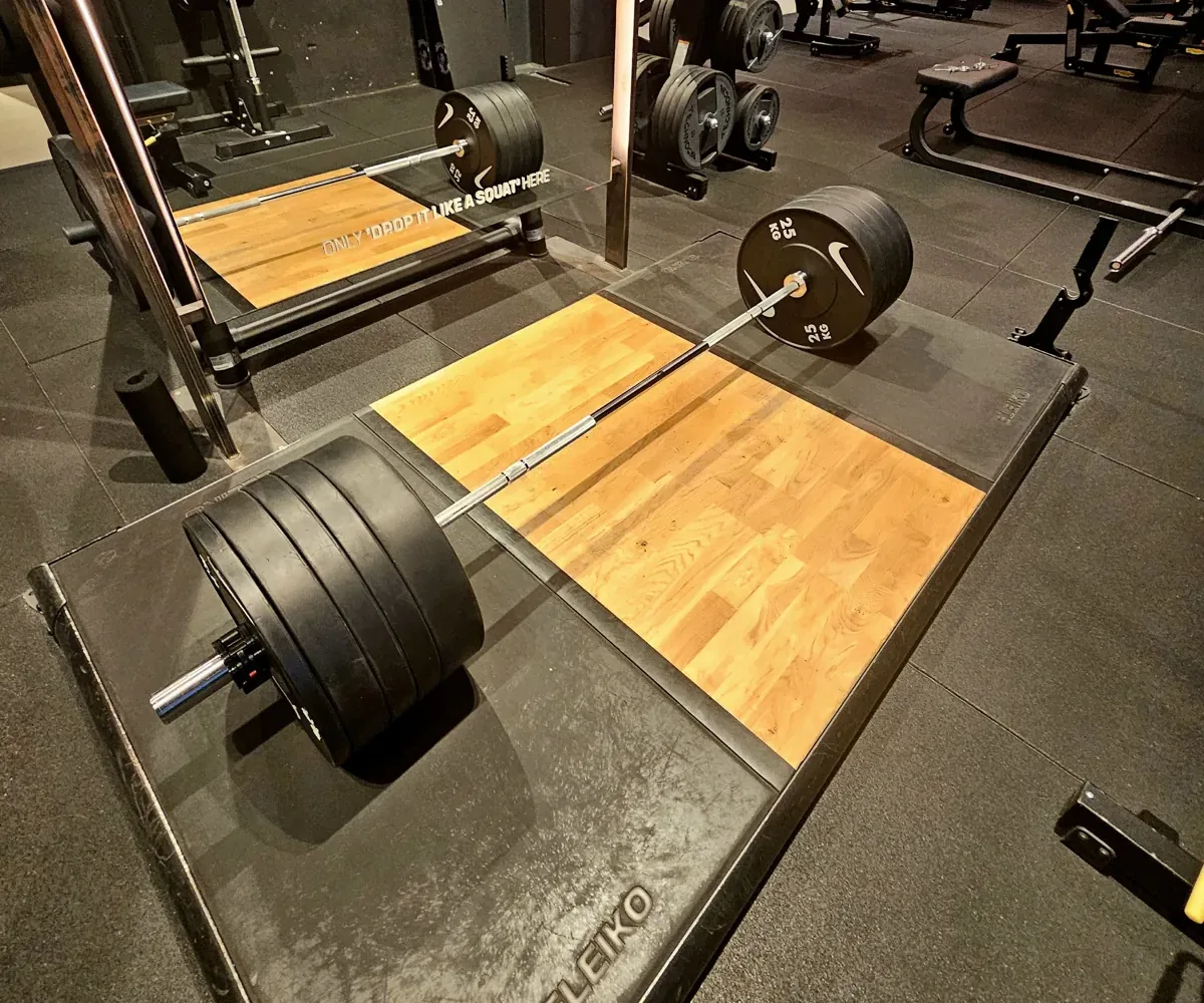 Een halter met zware schijven op een houten plateau in de sportschool, klaar voor een deadlift