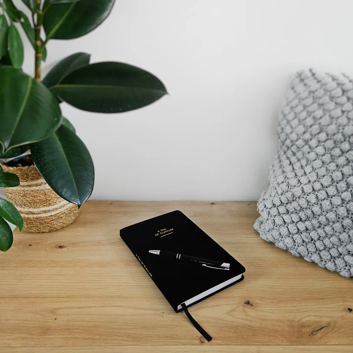 Journal met pen op een houten tafel naast een plant